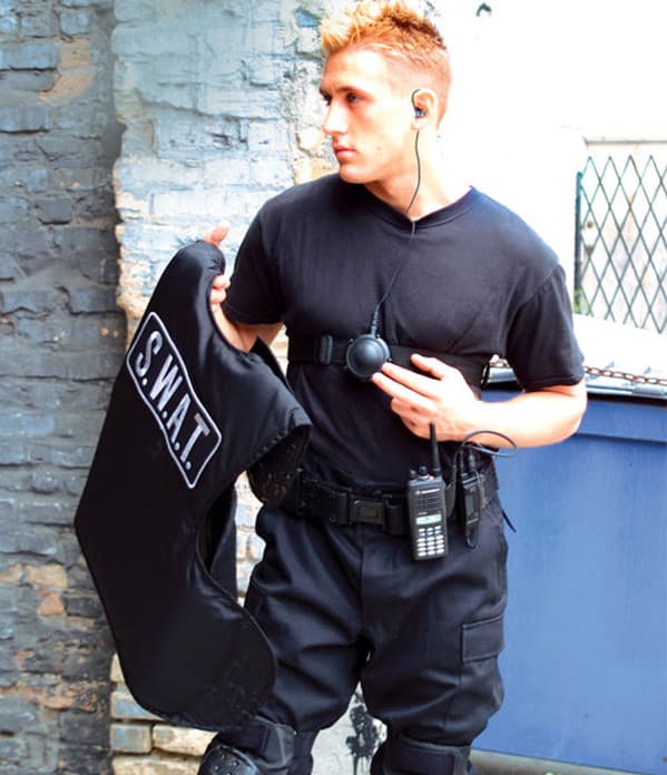 Muž v černé taktické uniformě se štítem S.W.A.T. používá speciální audio sestavu BDN6706 VoiceDucer VOX/PTT s Motorola radiostanicí.