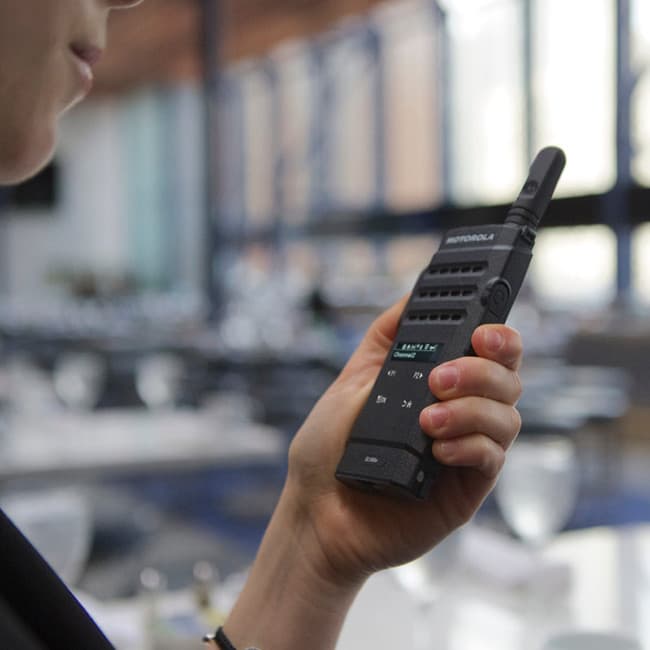 Dámská ruka drží radiostanici Motorola MOTOTRBO SL2600 UHF, detail displeje a ovládacích prvků.