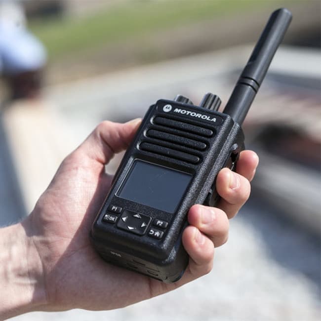 Detailní záběr na radiostanici Motorola MOTOTRBO™ DP3661e v ruce, s ostrým zaostřením na displej a ovládací prvky.